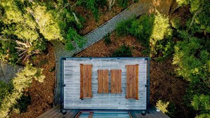 Une terrasse en bois avec une rambarde en métal, entourée d’un feuillage verdoyant et luxuriant.