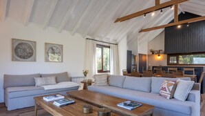 Un vaste espace de vie comprenant un grand canapé, une table basse en bois et un coin repas avec des chaises et une table.