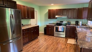 A kitchen with wooden cabinets, a stainless steel refrigerator, a stove, and a microwave. - Private 16-Acre Escape w/ Creek • Peaceful & Quiet • Fire Pit, Hiking & Lake (Hampton)