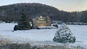 A snowy landscape with a sign for 'Sugar Mountain Skiing' and a Christmas tree. - Private 16-Acre Escape w/ Creek • Peaceful & Quiet • Fire Pit, Hiking & Lake (Hampton)