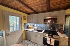 A compact kitchen with a wooden ceiling, a microwave, a stove, and a sink. - Crows Nest (Savannah)