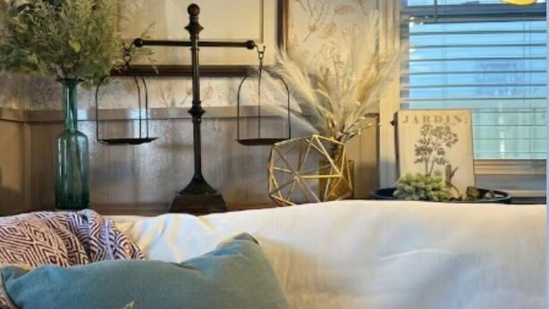 Een kamer met een bed, een wandweegschaal, een lijst met een afbeelding en een raam met jaloezieën.