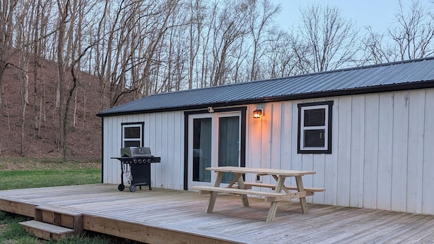 Un petit bâtiment d’un seul étage, doté d’une terrasse en bois, d’un barbecue et d’une table de pique-nique.
