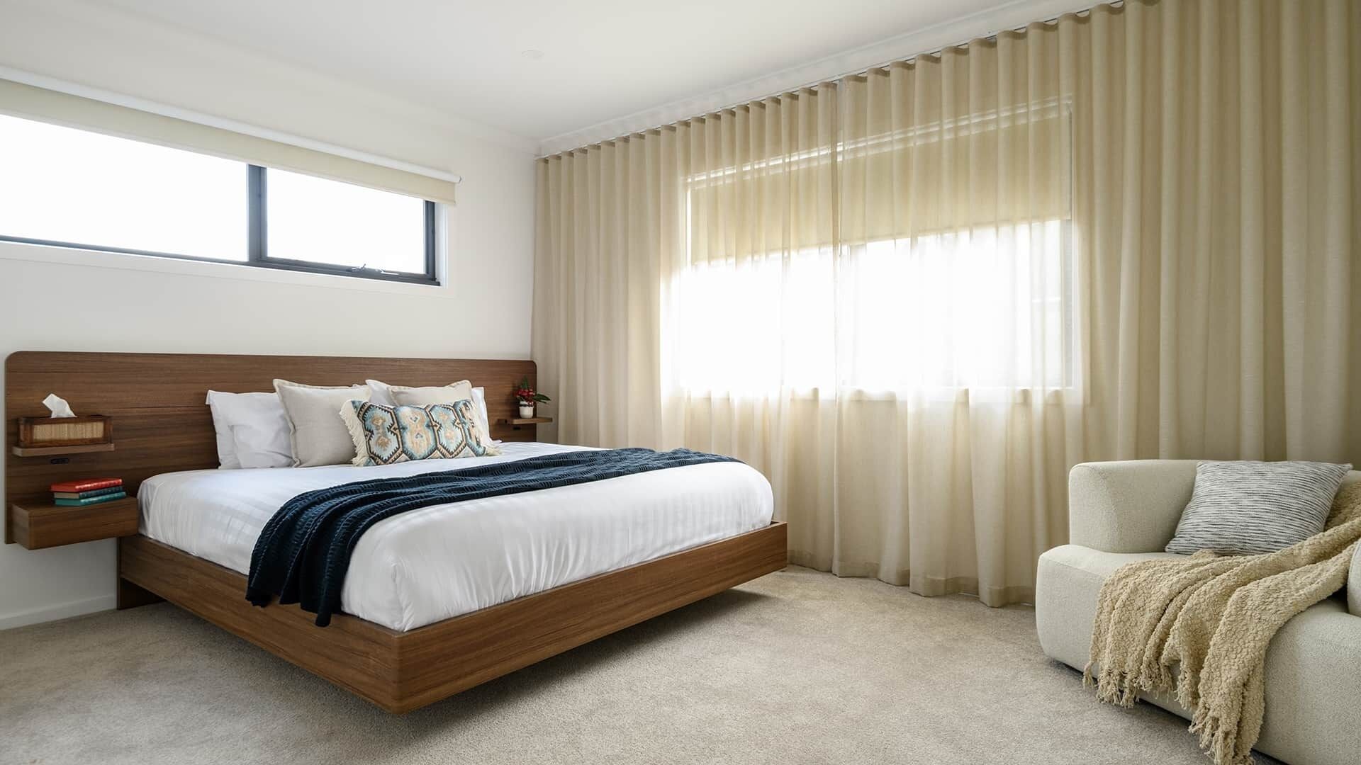 A bedroom with a wooden bed, a bedside table, a chair, and a window with curtains.