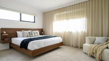 A bedroom with a wooden bed, a bedside table, a chair, and a window with curtains.