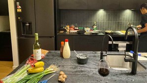 Une cuisine équipée d’un réfrigérateur, d’un évier et de divers aliments disposés sur le plan de travail.