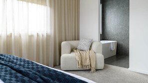 A modern bedroom with a bed, a chair, and a bathtub. - Sakura Lodge in Daylesford Victoria (Daylesford)