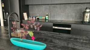 A modern kitchen with a black countertop, a sink, and a coffee maker. - Sakura Lodge in Daylesford Victoria (Daylesford)