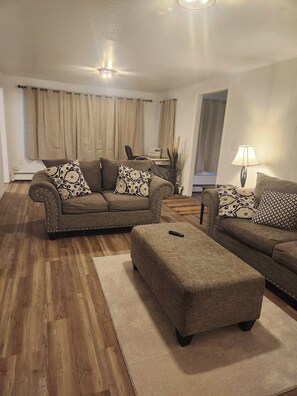 A living room with a sofa set, ottoman, and a lamp. - Charming 2-bedroom apartment in Wasilla perfect for your getaway (Wasilla)