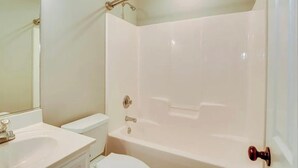 Une salle de bain avec une baignoire, des toilettes, un lavabo et un miroir.