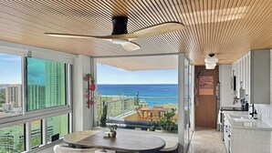 Eine moderne Küche mit Meerblick, eine Essecke mit Tisch und Stühlen sowie ein Balkon mit Pflanzen.