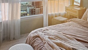Ein Schlafzimmer mit großem Fenster, einem Bett, einem Schreibtisch und einem Stuhl.