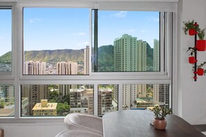 A room with large windows offering a view of surrounding buildings and hills. - Sea to Sky Corner Penthouse Ocean and Diamond Head Views (Honolulu)