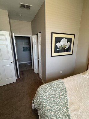 Un dormitorio con cama, un cuadro en la pared y un pasillo que lleva a otra habitación.