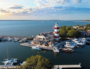 A marina with boats, a lighthouse, and a building with multiple decks. - Family Sea Pines Oasis - Walk to Beach, Pool, Golf (Hilton Head Island)