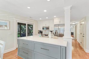 A modern kitchen with white cabinets, a large island, and a stainless steel refrigerator. - Family Sea Pines Oasis - Walk to Beach, Pool, Golf (Hilton Head Island)