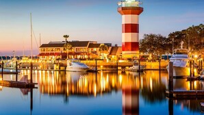 Un faro, un puerto deportivo y edificios frente al mar.