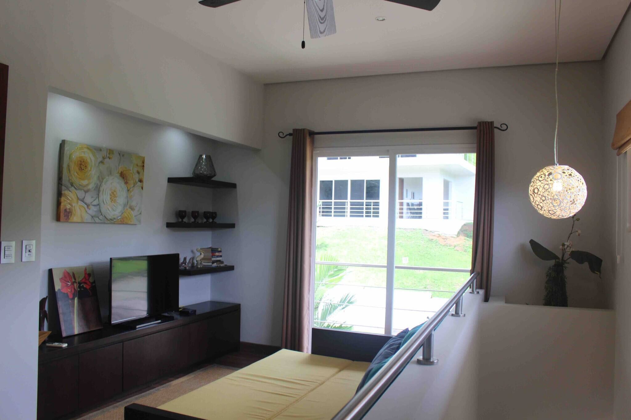 Una sala de estar moderna con un televisor de pantalla plana, obras de arte y vistas a través de un ventanal.