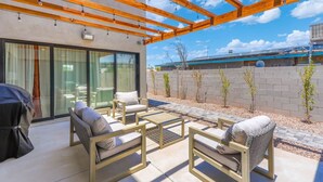 An outdoor patio with wicker furniture, a pergola, and a view of a building in the background. - New Downtown Chandler | Family & Pet-Friendly (Chandler)