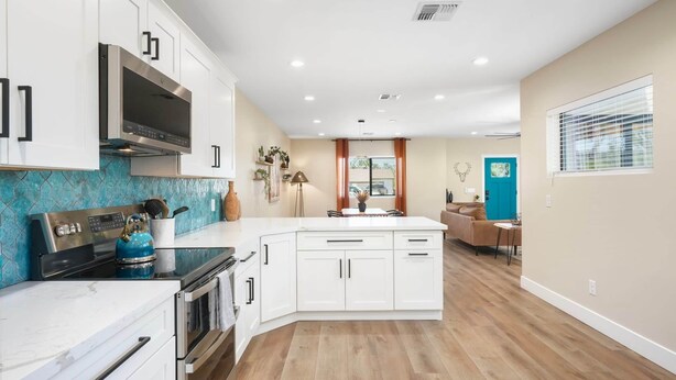 A modern kitchen with white cabinets, a built-in oven, and a large island. - New Downtown Chandler | Family & Pet-Friendly (Chandler)