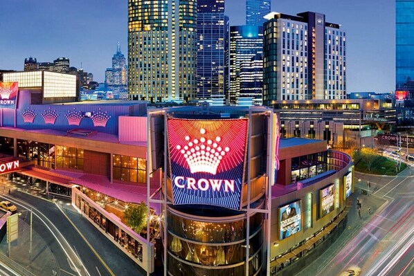 Ein Hotel mit einem gut sichtbaren 'Crown'-Schild, umgeben von Hochhäusern und einer belebten Straße.