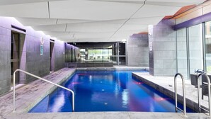 Een binnenzwembad met glazen wanden, betegelde vloer en modern architectonisch ontwerp.