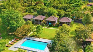 Un resort con varias edificaciones tipo bungalow rodeado de exuberante vegetación y montañas al fondo.