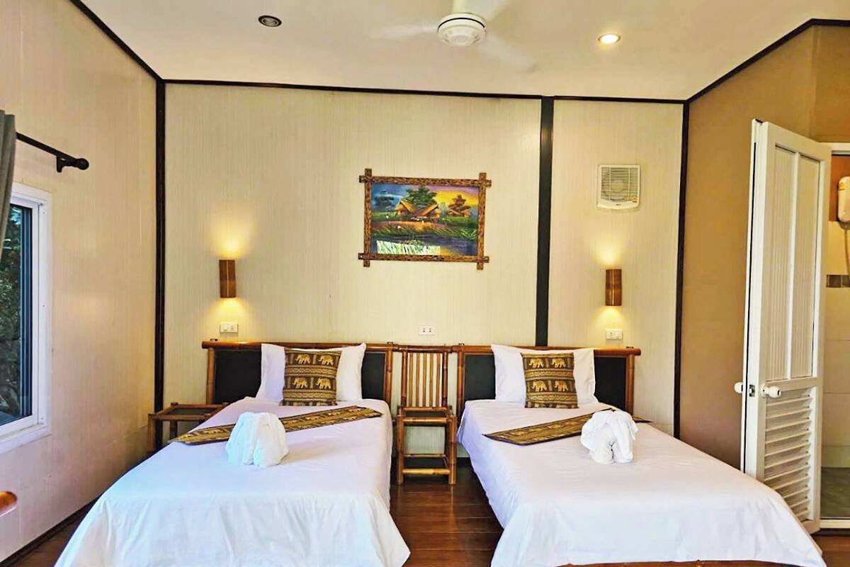 Une chambre d’hôtel avec deux lits, un tableau au mur et une fenêtre.