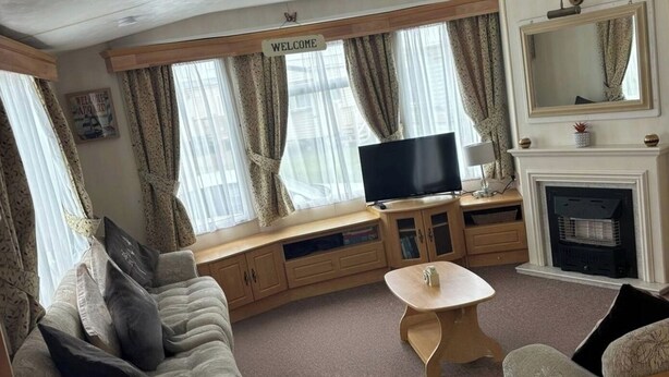 Ein gemütliches Wohnzimmer mit einer Couch, einem Fernseher, einem Kamin und einem 'Welcome'-Schild.
