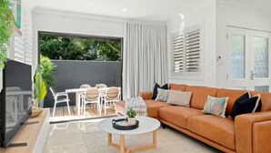 A modern living room with a sofa, coffee table, and a dining area with chairs.