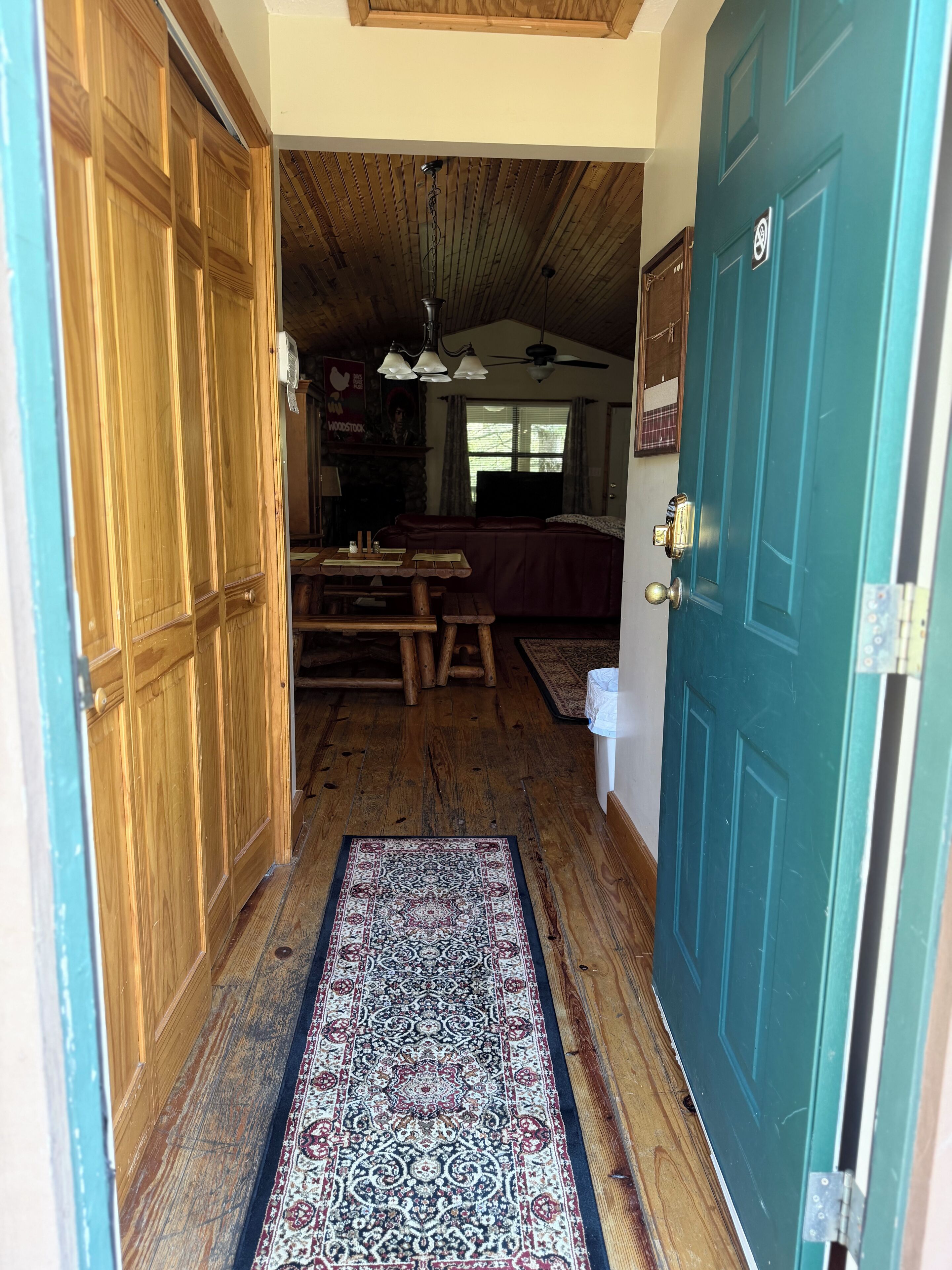 Un interior de madera con una puerta azul, una alfombra estampada y un ventilador de techo.
