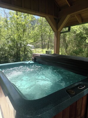 Ein Whirlpool mit Holzterrasse und Blick auf Bäume.
