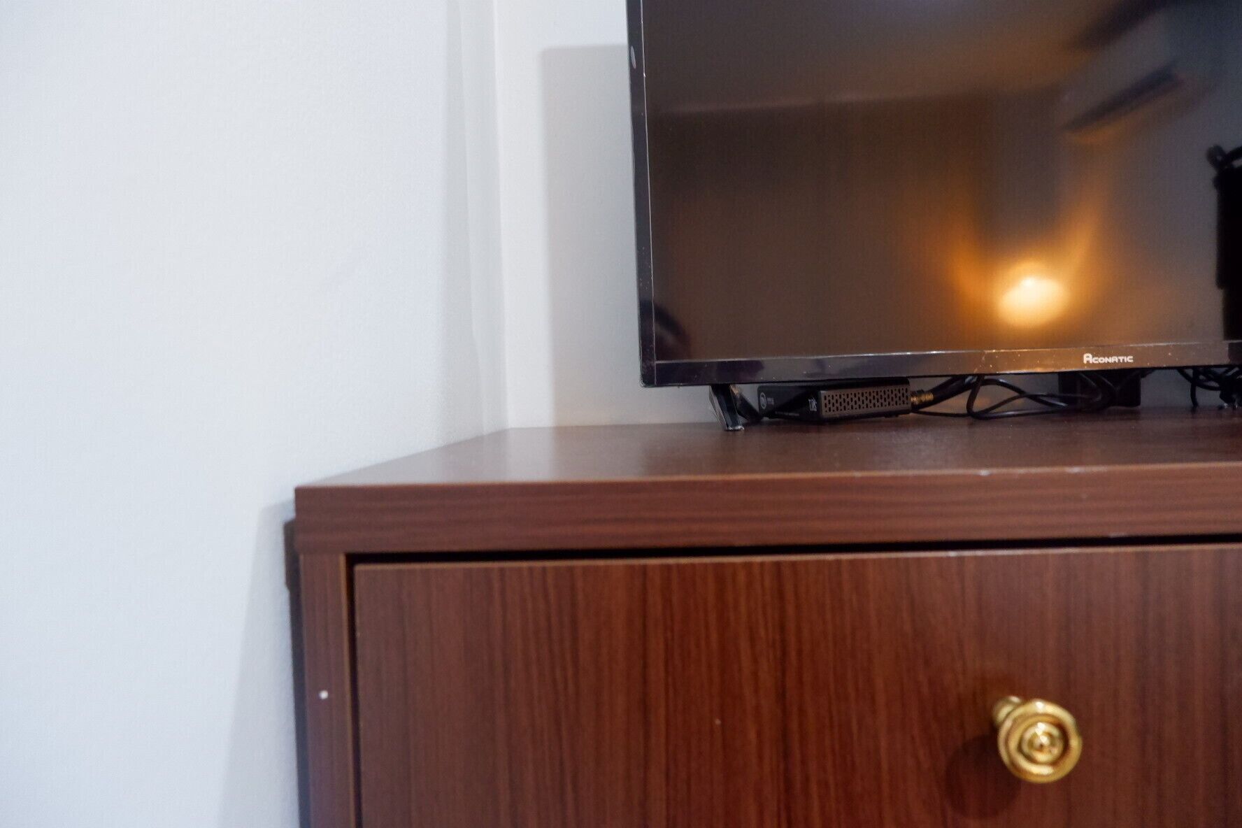 A television on a wooden cabinet with a visible brand name.