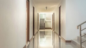 A hallway with a staircase, doors, and a ceiling light fixture. - TP Residence (Bangkok)