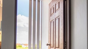 A room with a wooden door, a window with vertical blinds, and a tiled floor. - TP Residence (Bangkok)