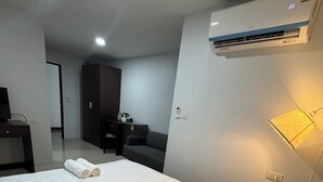 A hotel room with a bed, a desk, a wardrobe, and an air conditioning unit. - TP Residence (Bangkok)