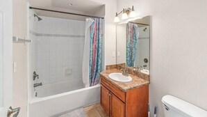 Ein Badezimmer mit einer Badewanne, einem Waschbecken, einem Spiegel und einer Duschvorhang.