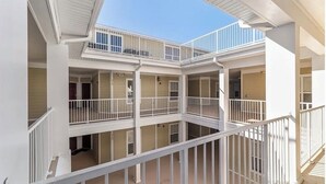 Ein mehrgeschossiges Gebäude mit Balkonen und Geländern, das einen zentralen Innenhof und mehrere Zimmer umfasst.