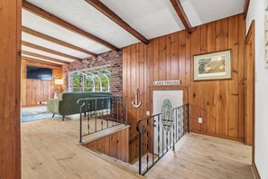 Een houten interieur met een trap, een open haard en een bord waarop 'LAKE HOUSE' staat.
