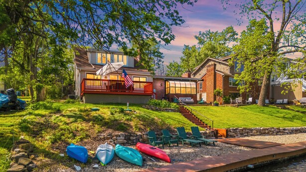 Une maison avec une terrasse, une piscine et des kayaks.