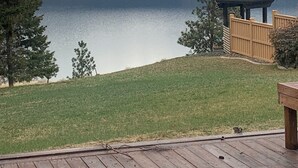 Vistes a un llac amb terrassa, arbres i un paisatge urbà llunyà.