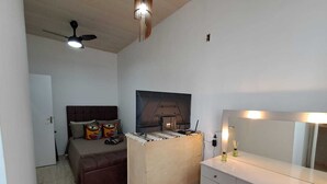 Une chambre à coucher comprenant un lit, une commode, un miroir et un ventilateur de plafond.