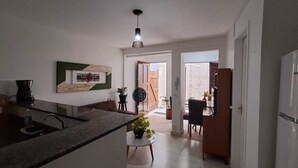 Une cuisine dotée d’un îlot central, un coin repas avec une table et des chaises, et une vue sur la pièce adjacente.