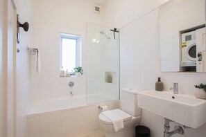 Une salle de bain moderne avec une douche à parois de verre, des toilettes, un lavabo et une fenêtre.