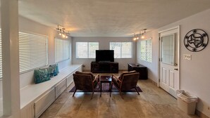 Un salon avec un téléviseur, des sièges et des fenêtres.