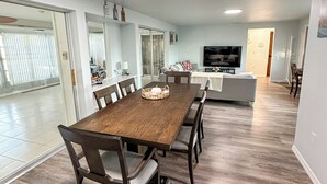 Een moderne keuken met een eethoek, houten vloeren en een grote televisie.