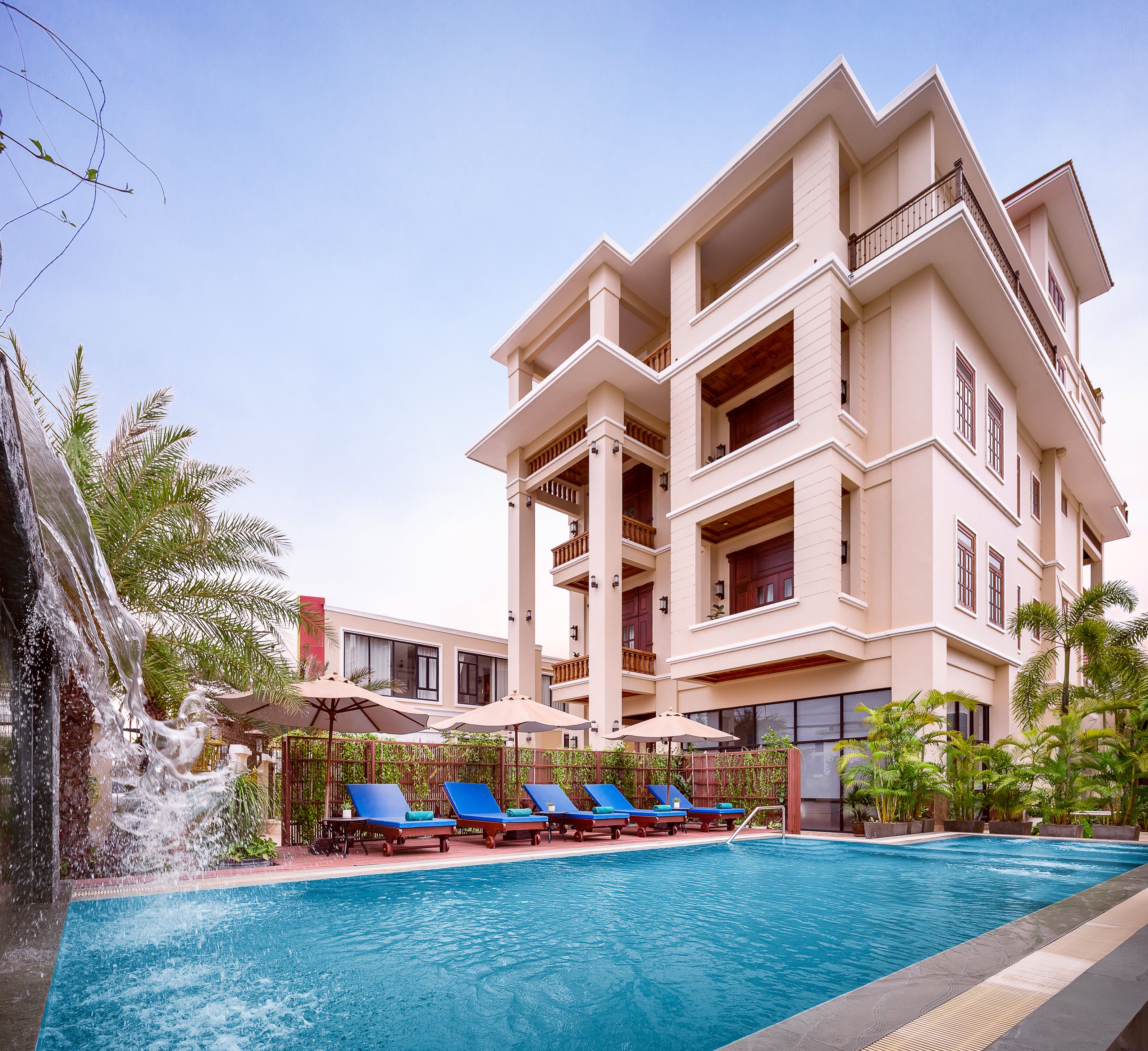 Un hotel con piscina, varios balcones y una cascada.