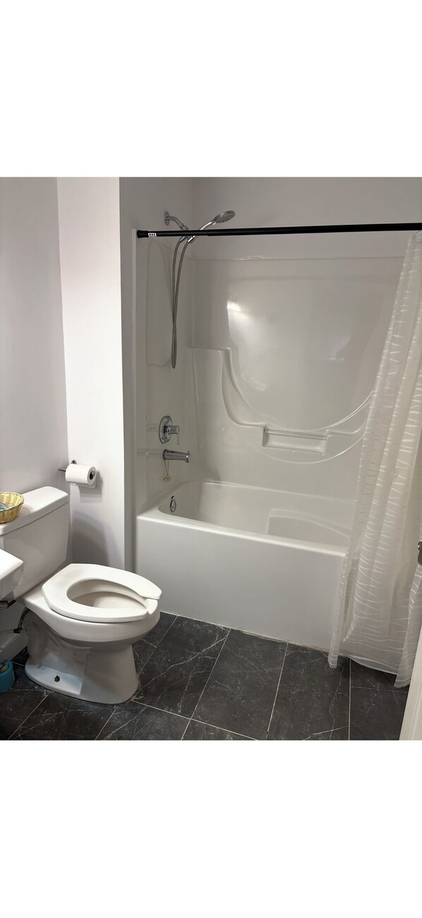 Un baño con inodoro, bañera y cortina de ducha.