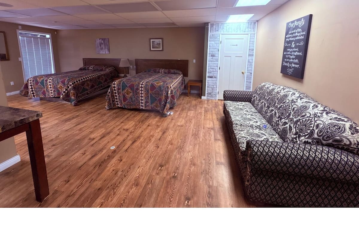 A room with a wooden floor, two patterned sofas, a table, and a door.