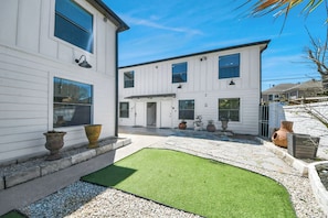 A two-story white house with a paved patio, a small lawn, and decorative planters. - Arbor Flats #6 in the Heart of Houston (Houston)